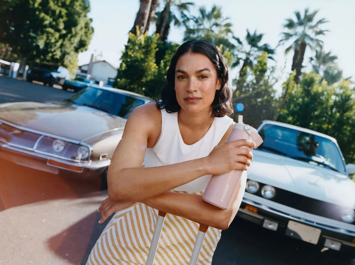 Uma mulher segurando a garrafa Stanley dela depois de ter refletido se era melhor ter a Stanley Aerolight ou Classic para todos os dias.