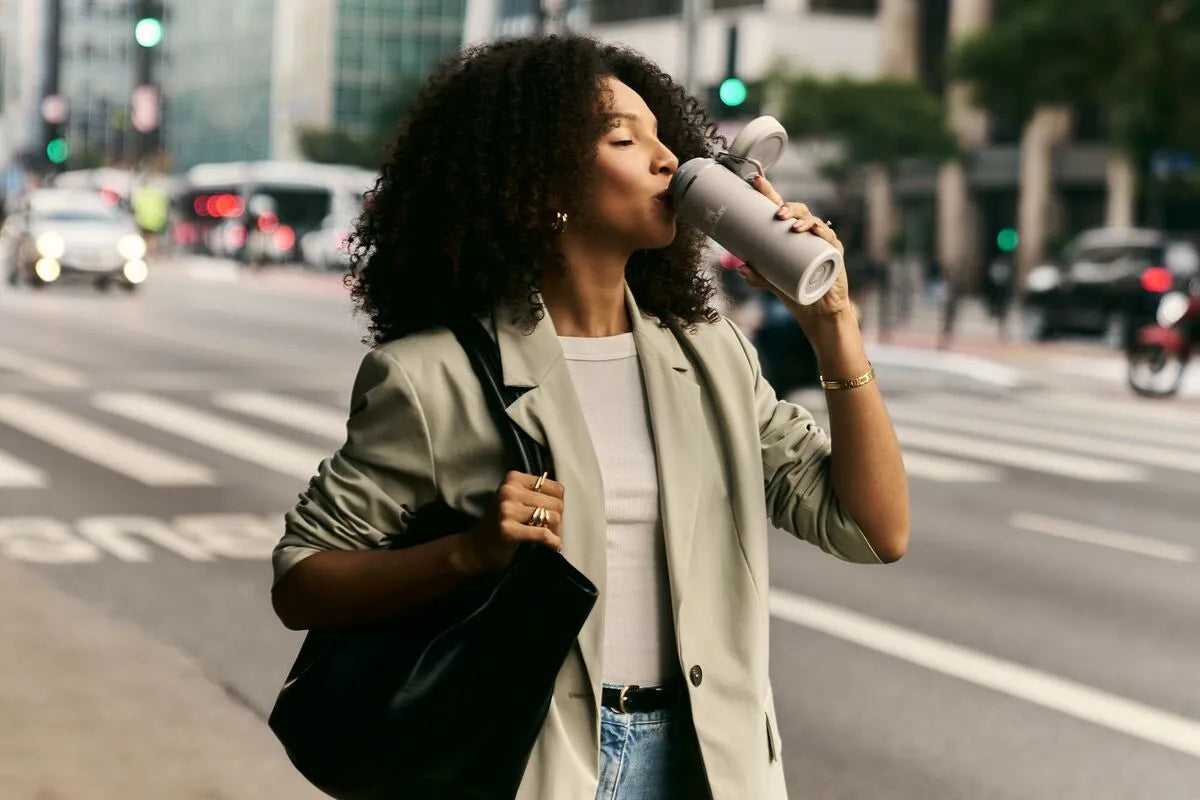 Uma mulher bebendo sua bebida favorita na Twist Flip que ela comprou no novo site Stanley.