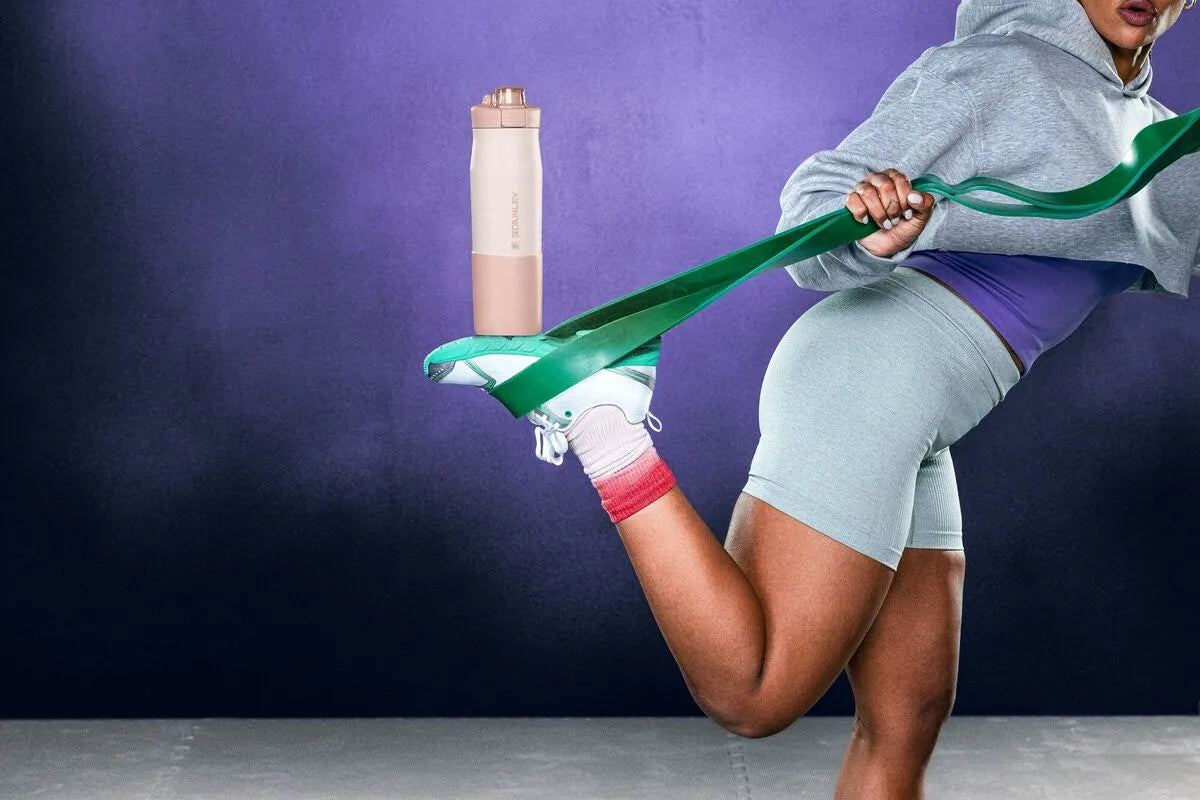 Uma mulher se exercitando enquanto segura a Vitalize Tempo Bottle com os pés.