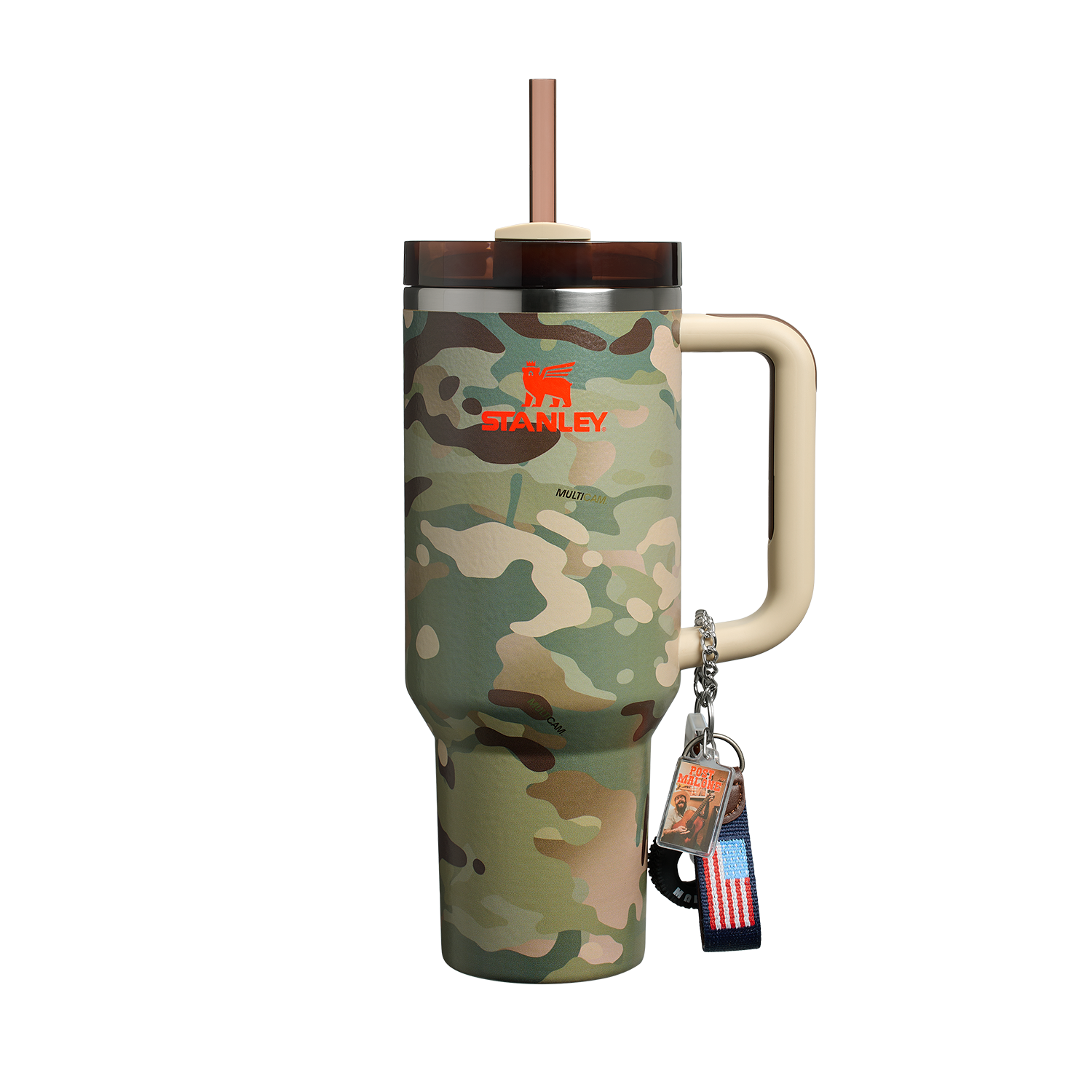 Mostra um copo térmico "Stanley Quencher" com estampa camuflada, alça bege e tampa com canudo. Ele tem o logotipo "Stanley" em vermelho e branco. Pendurado na alça, há um chaveiro com uma bandeira dos EUA e um pingente com a inscrição "Best Dad Ever" e uma imagem de um homem.